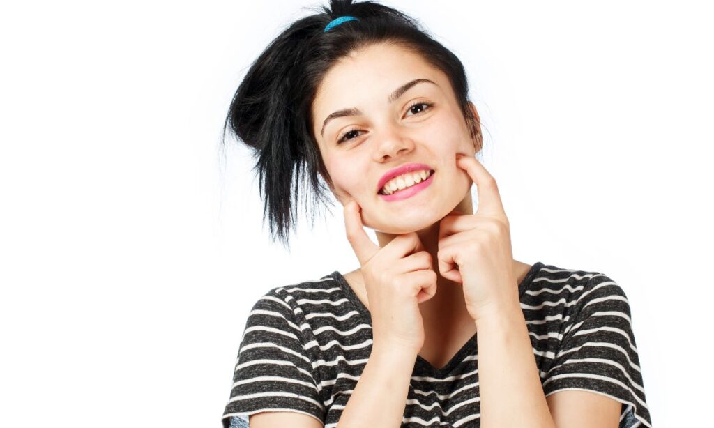 girl smiling and placing fingers in her mouth